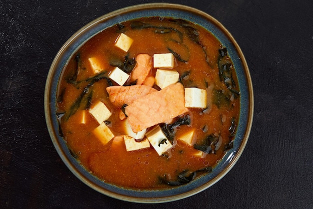 Japanese miso soup in a gray bowl on the black table horizontal view from above