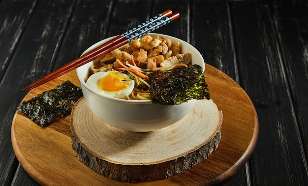 Japanese ramen soup with chicken, egg, garlic and noodles on a dark wooden background. Asian Miso Ramen noodles.