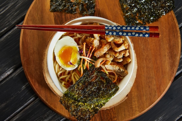 Japanese ramen soup with chicken, egg, garlic and noodles on a dark wooden