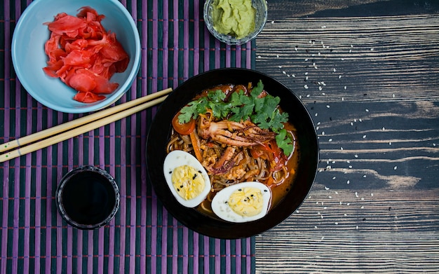 Japanese ramen with seafood, herbs and pickled eggs on a dark surface