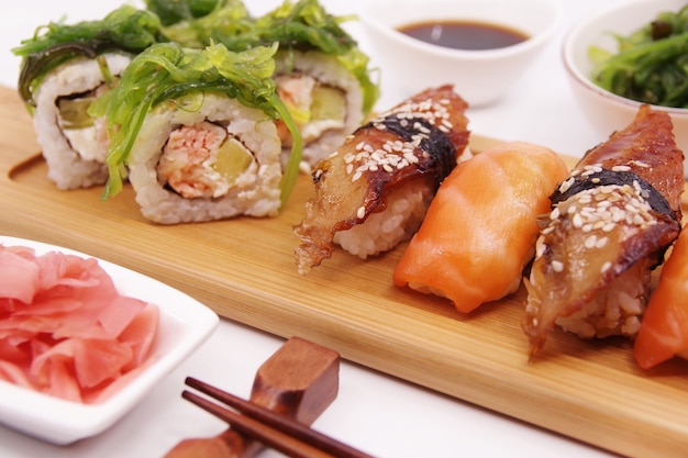 Japanese sushi food on a wooden tray, served with ginger, soy sauce and seaweed salad.