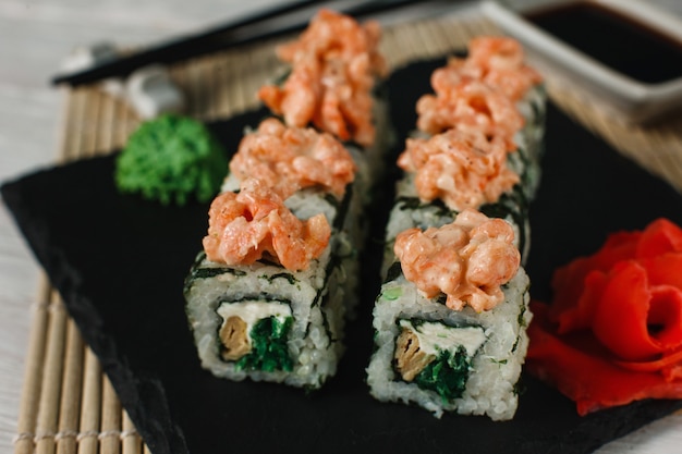 Japanese sushi, national cuisine, seafood, food art. Delicious set of uramaki served on black slate. Restaurant menu photo, close up.