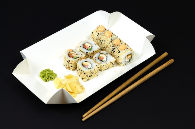 Japanese sushi rolls in white eco paper disposable box on dark background