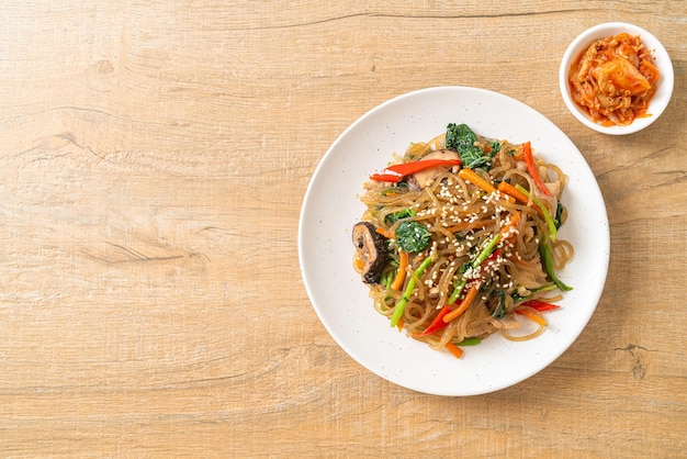 japchae or stir-fried Korean vermicelli noodles with vegetables and pork topped with white sesame - Korean traditional food style