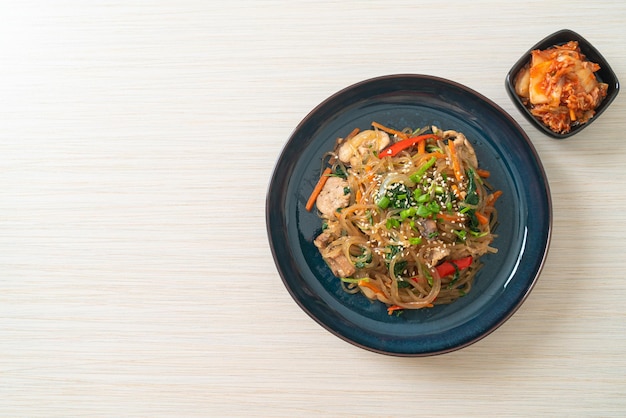 Japchae or stirfried Korean vermicelli noodles with vegetables and pork topped with white sesame