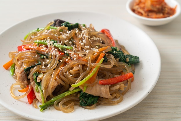 Japchae or stirfried Korean vermicelli noodles with vegetables and pork topped with white sesame