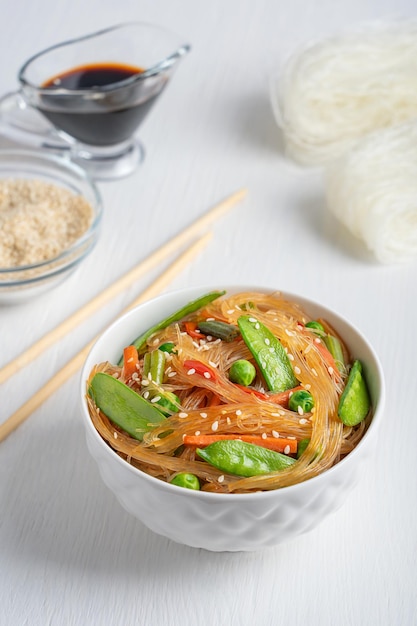 Japchae vegan korean stirfried glass noodles with vegetables in bowl with chopsticks soy sauce