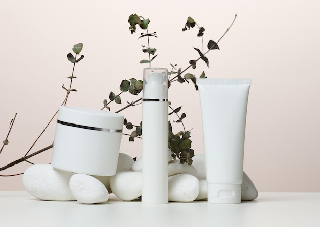 Jar bottle and empty white plastic tubes for cosmetics on a beige background