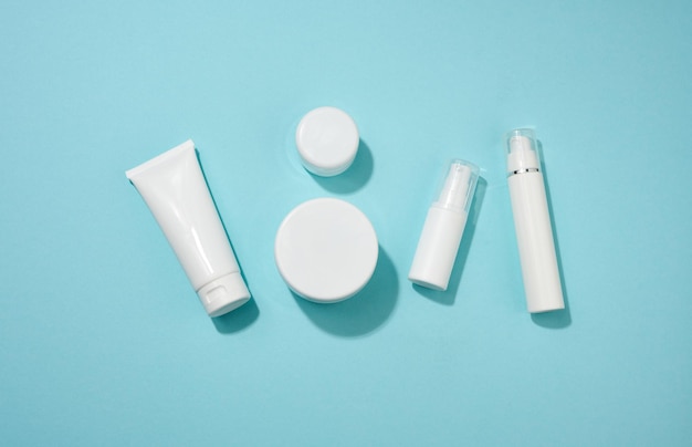 Jar, bottle and empty white plastic tubes for cosmetics on a blue background. Packaging for cream, gel, serum, advertising and product promotion, mock up