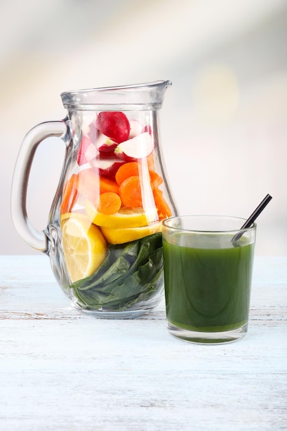 Jar of cut vegetables and glass of fresh vegetable juice with vegetables on wooden table