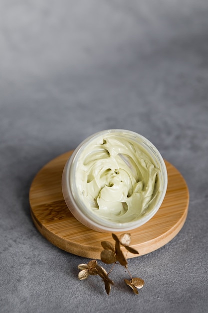 A jar of face cream on a wooden stand on a gray table. Set for skin and body care beauty products