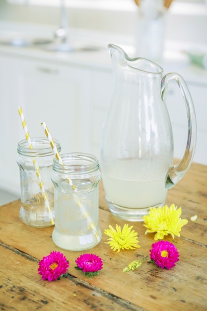 Jar and glasses with lemonade juice in the kitchen