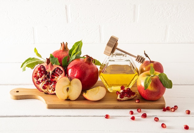 A jar of honey and spindle on a wooden board with ripe fruits pomegranates and apples traditional food for the holiday of Rosh Hashanah front view