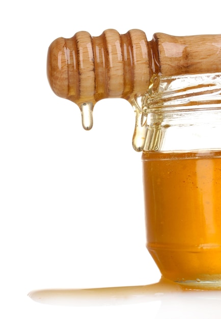 Jar of honey and wooden drizzler isolated on white