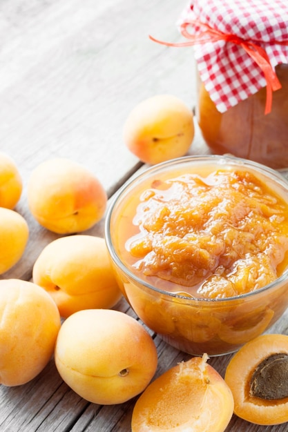 Jar of jam and ripe apricot fruits on table