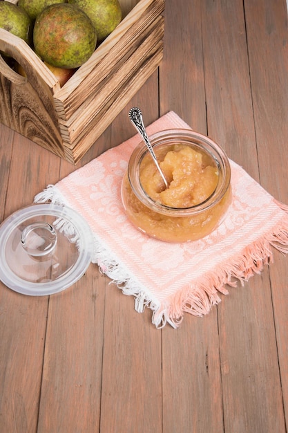 A jar of mashed pears and fresh pears in a wooden box on a wooden background