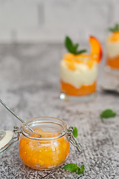 Jar of peach jam on white brick wall background