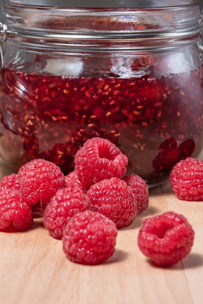 A jar of raspberry jam with fresh berries on the table