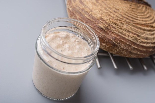 Jar of sourdough starter yeast next to a freshly baked home made bread