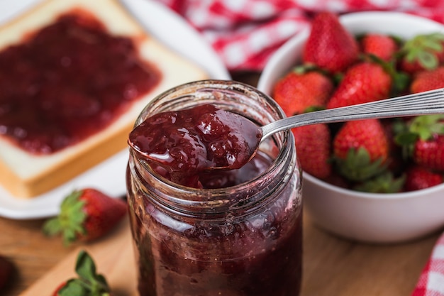 Jar of strawberry jam on  wooden background from top view 