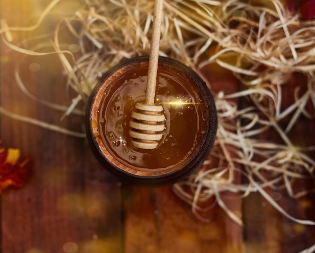 A jar of sweet honey in a bucket on a wooden table in the garden with flowers for breakfast delicious food