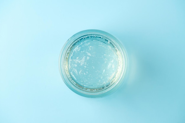 Jar of transparent cosmetic gel on blue background. Top view