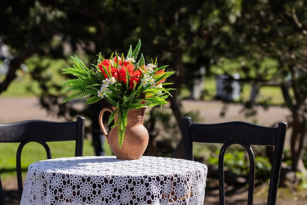 A jar with a bouquet of flowers on a table with a tablecloth outdoors