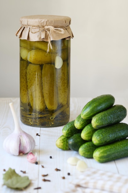 A jar with cucumbers prepared for pickling and ingredients for the marinade garlic dill horseradish leaves currant leaves against the background of a box with readymade canned cucumbers