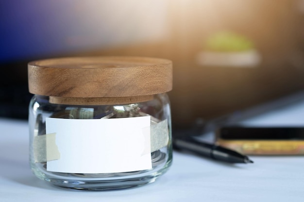 Jar with empty note paper isolated in office background Concept saving money