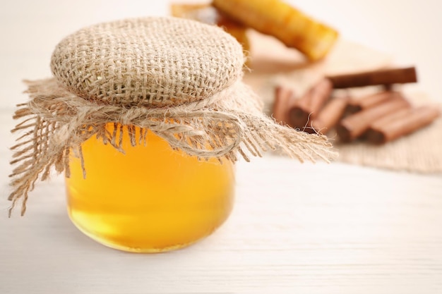 Jar with honey on white wooden background