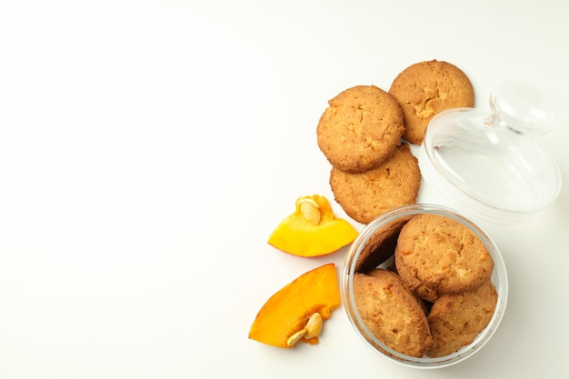 Jar with pumpkin cookies on white background.