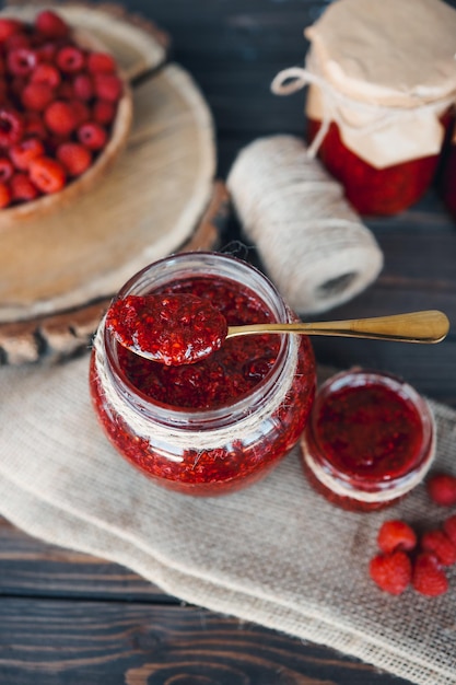 Jar with a spoon and raspberry jam with craft decor