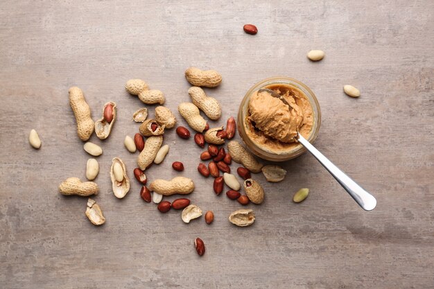 Jar with tasty peanut butter on grey