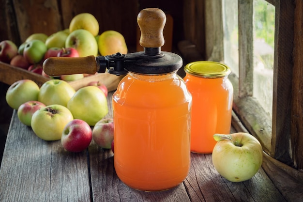 Jars of fresh apple juice apple fruits and can lid closing machine for canning on table