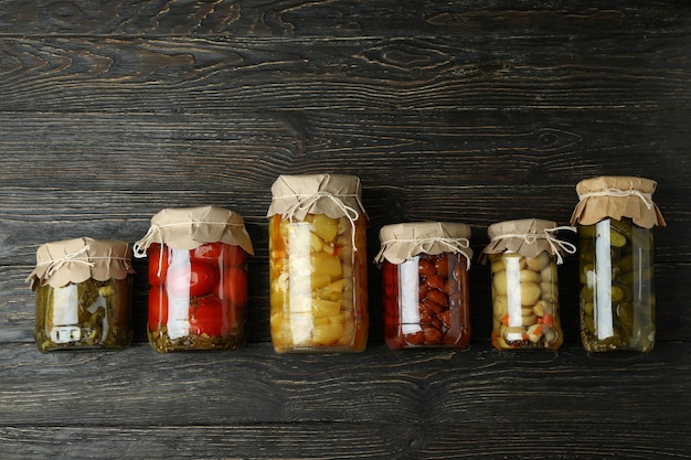 Jars of pickled vegetables on rustic wooden background