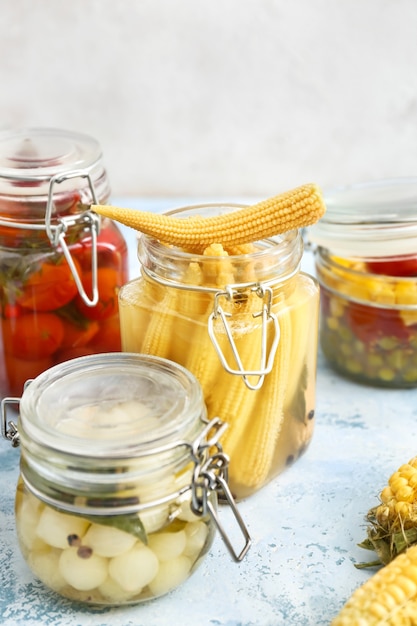 Jars with different canned vegetables on table