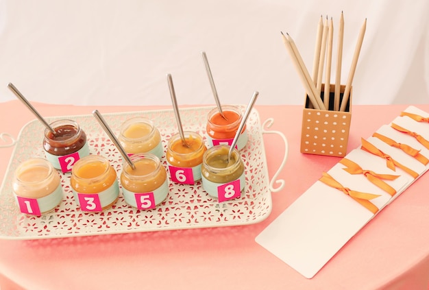 Jars with different puree on table Game Guess taste for baby shower party