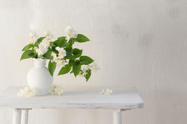 Jasmine flowers in ceramic vase on white background