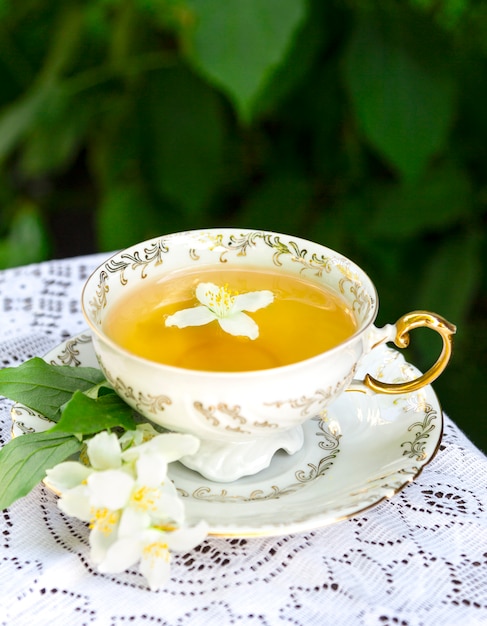 Jasmine tea in a porcelain Cup and jasmine flowers on lace table cloth 