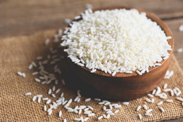 Jasmine white rice in wooden bowl and harvested rice on sack, harvest rice and food grains cooking concept