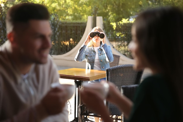 Jealous ex girlfriend spying on couple in outdoor cafe