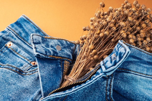 Jeans and dry linen on a bright brown background Natural denim fabric concept Autumn fashion collection of denim clothing Ecofriendly clothing made from recycled materials