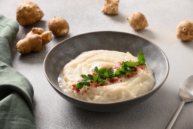 Jerusalem artichoke puree decorated fresh parsley in bowl