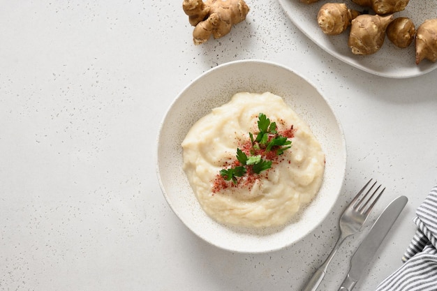 Jerusalem artichoke puree decorated fresh parsley in bowl