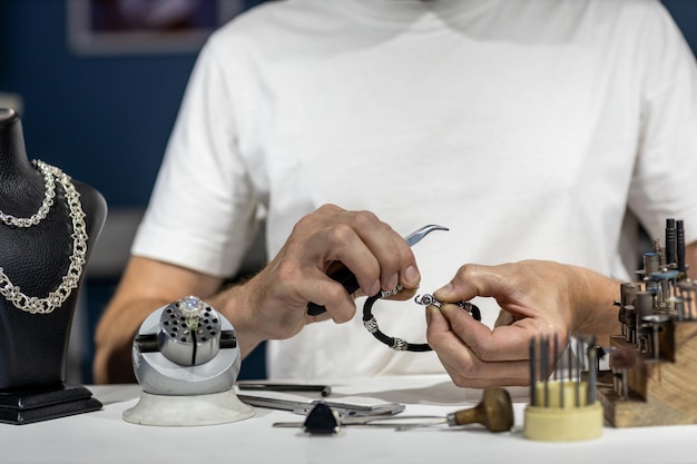 Photo jewelers hands with jewelry and tool closeup