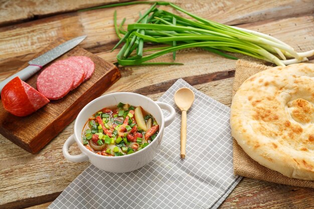 Jewish cuisine bean soup cholit on a gray napkin next to green onions sausage and flatbread