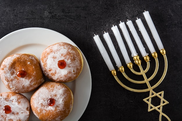 Photo jewish hanukkah menorah and sufganiyot donuts on black