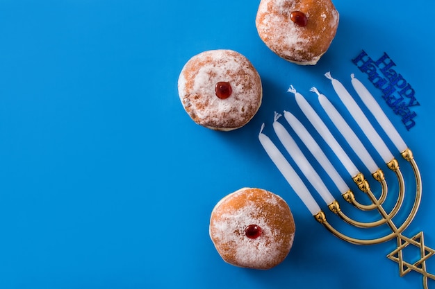 Photo jewish hanukkah menorah and sufganiyot donuts on blue  top view copyspace