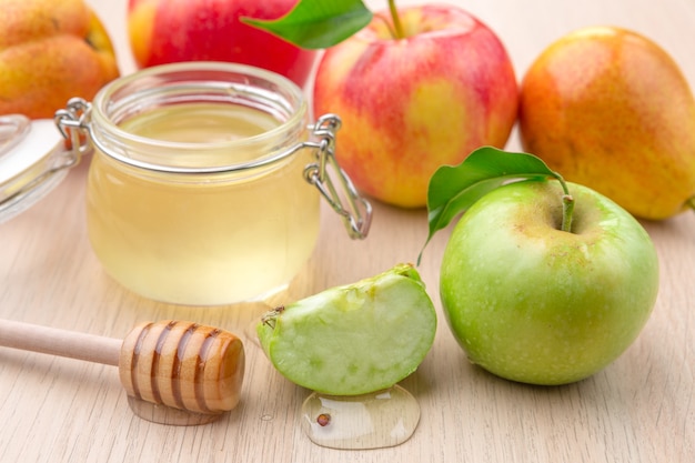 Jewish holiday Rosh Hashanah background with honey and apples on wooden table.