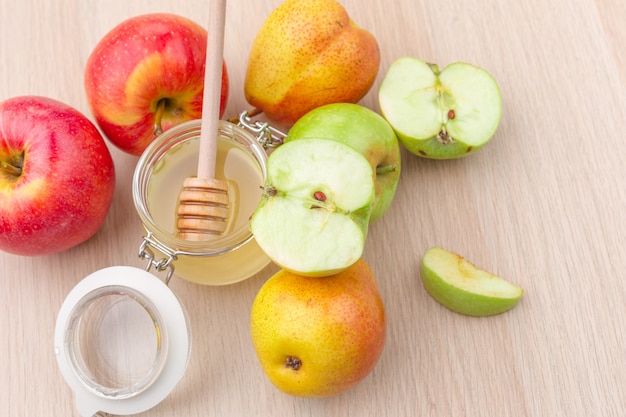 Jewish holiday Rosh Hashanah with honey and apples on wooden table.